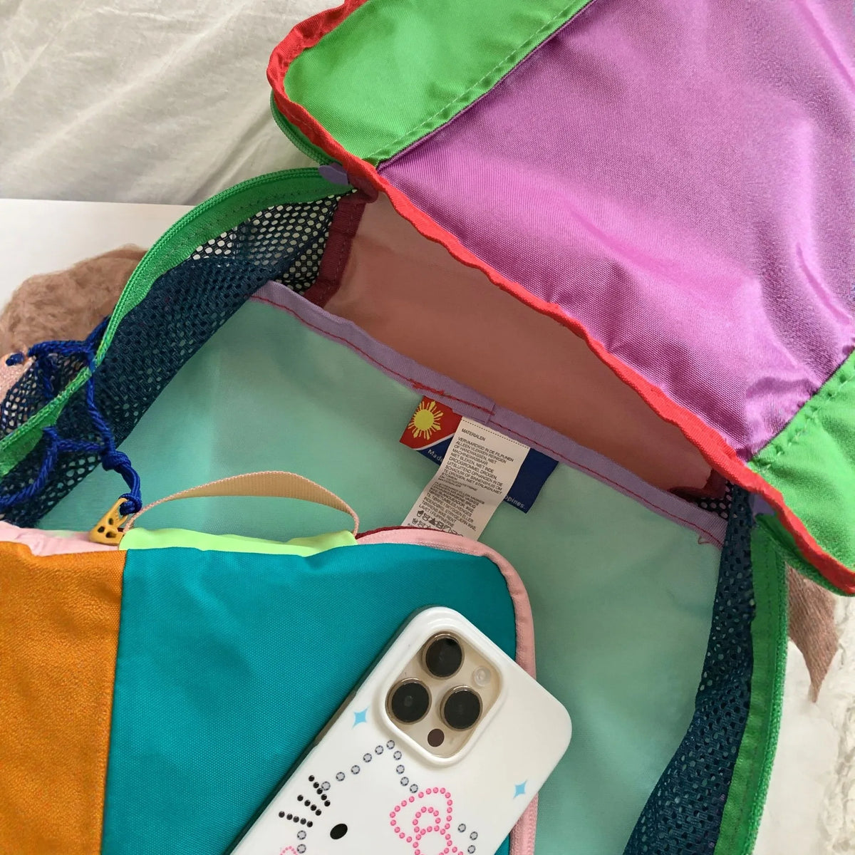 A colorful waterproof toiletry bag set featuring pink, green, and orange nylon construction with a white smartphone visible i