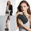 A close-up of a woman holding a black handwoven clutch evening bag against a light gray background.