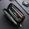 A dark brown leather wallet with multiple card slots is shown open on a black surface, next to a small black accessory.