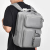 A person is wearing a gray large capacity travel backpack with multiple compartments.