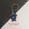 A hand sewn rhinestone beaded bag charm featuring purple and green stones on a gold-colored cord.