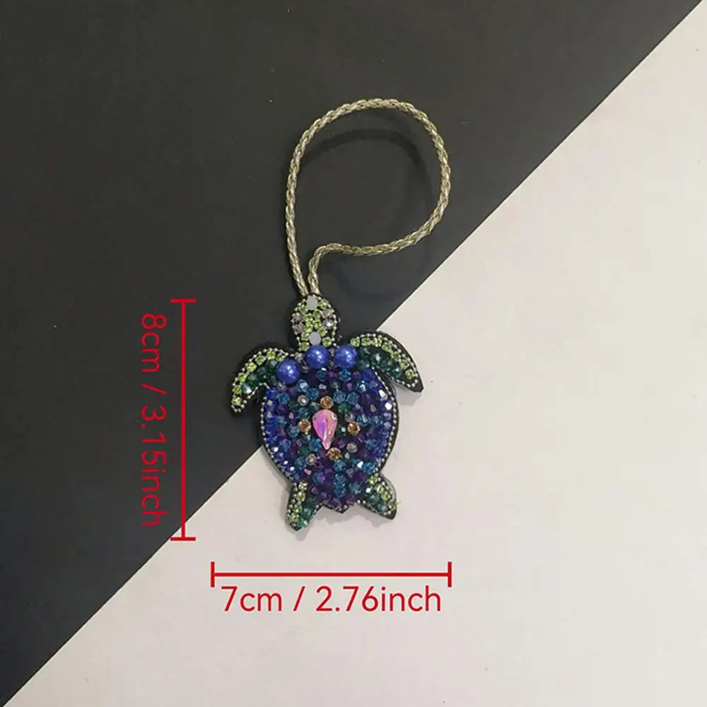 A hand sewn rhinestone beaded bag charm featuring purple and green stones on a gold-colored cord.