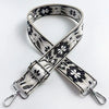 A beige and black patterned fabric strap for a crossbody bag, shown crossed.