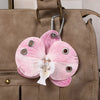 A pink orchid flower keychain attached to a brown leather handbag.