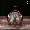 A vintage metal ashtray with a rose embossing design and windproof lid, shown on a wooden surface.