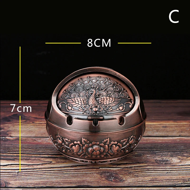 A vintage metal ashtray with a rose embossing design and windproof lid, shown on a wooden surface.