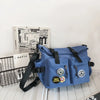 A blue nylon crossbody bag with black straps and decorative elements is shown next to a box labeled Daily and 365 Smiles.