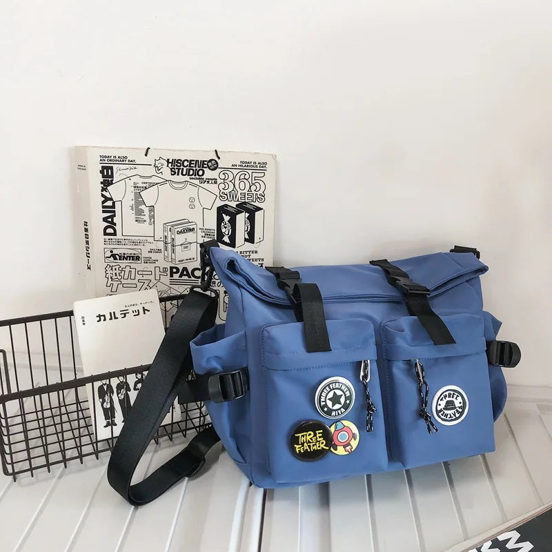 A blue nylon crossbody bag with black straps and decorative elements is shown next to a box labeled Daily and 365 Smiles.