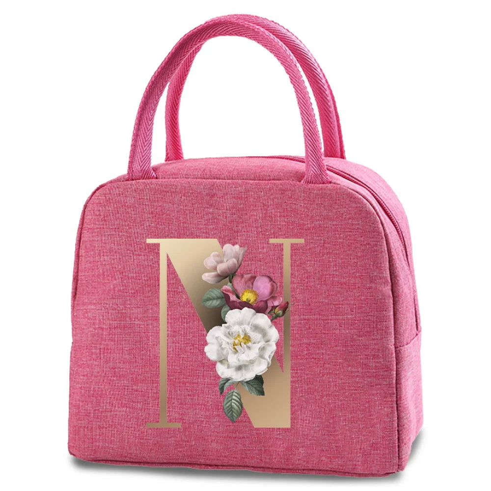 A pink insulated canvas lunch bag featuring a gold letter N and floral embroidery.
