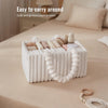 A white flannel diaper caddy organizer filled with various baby items is shown on a beige bed linen.