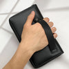 A hand holds a black multi-card men's commuter wallet with a leather strap.