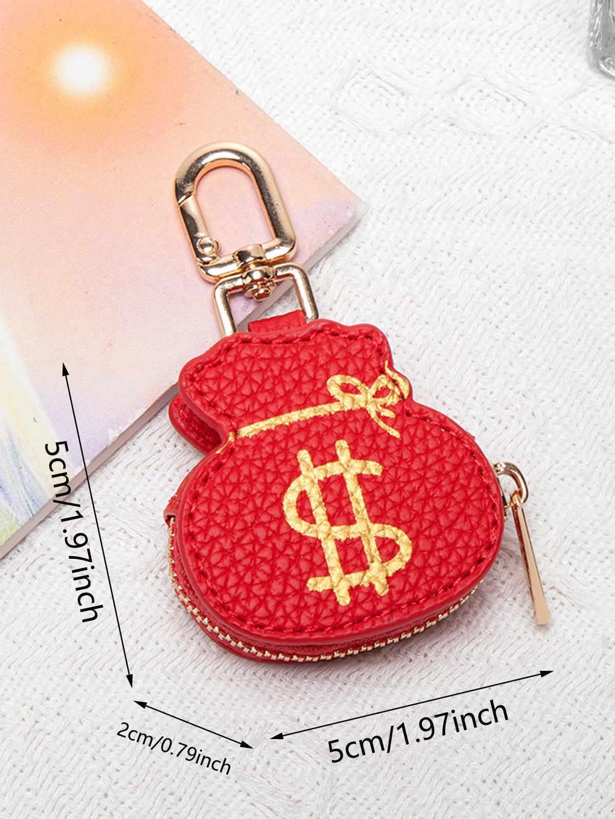 Cartera llavero con forma de corazón, moneda roja, hebilla dorada y signo de dólar amarillo.
