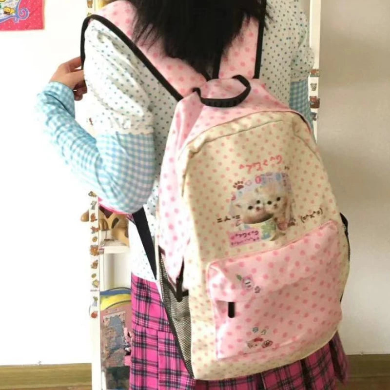 Sac à dos rose et blanc à motif de chat porté par une personne.