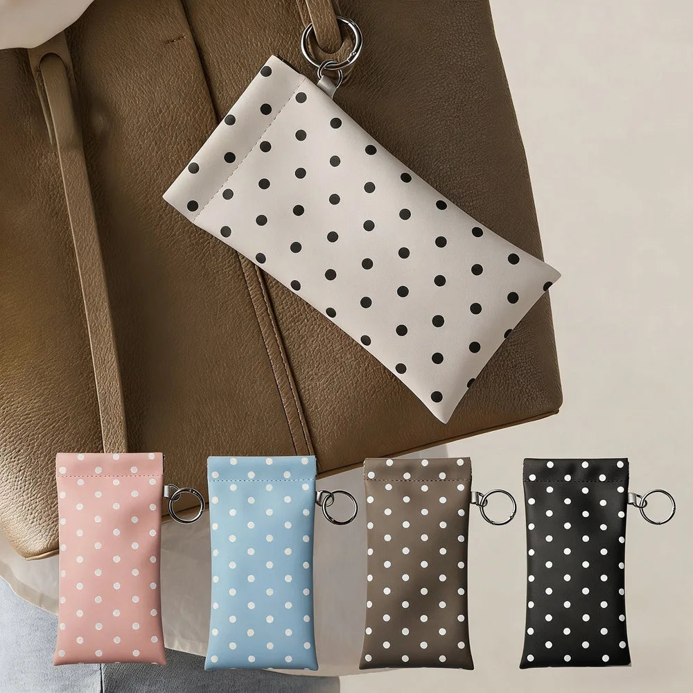 A brown leather pouch holds a white polka dot eyeglass pouch and a blue eyeglass pouch.