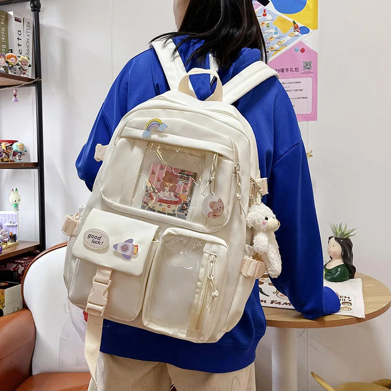 A woman wears a large white backpack with a blue shirt and beige pants, featuring a padded laptop compartment.