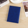A dark blue heart print passport cover travel wallet resting on a light wooden surface next to a photo.