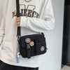 A woman wearing a white sweatshirt holds a black Quick-Dry Canvas shoulder bag.