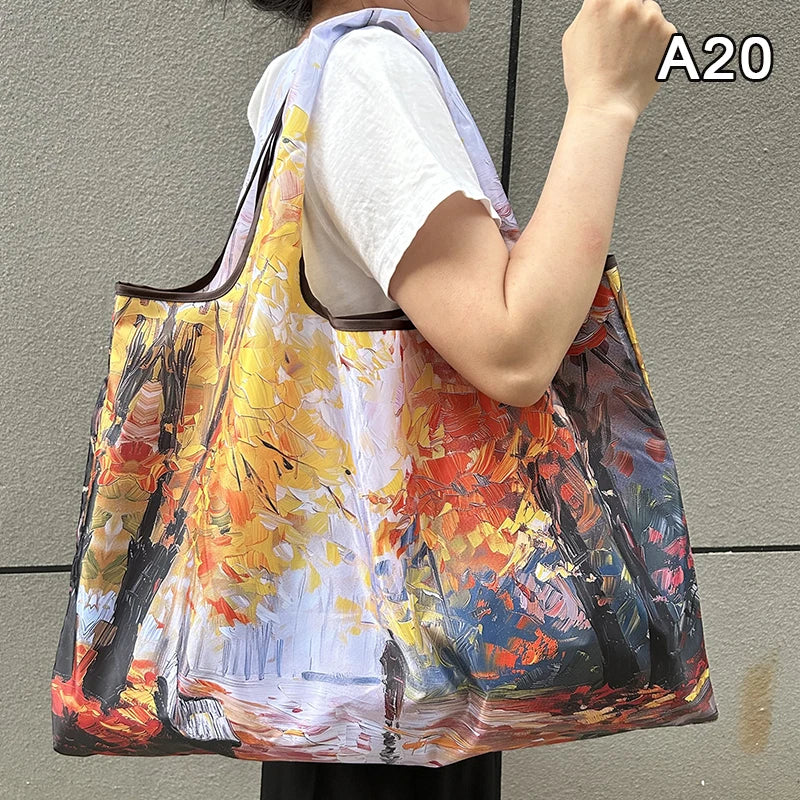 A person holds a large, colorful canvas shopping tote with an orange strap against a gray background.