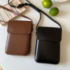 A brown vintage PU leather crossbody bag with a black adjustable strap next to a green lime.