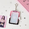 A pink and black angel wings photocard holder with a clear display case and a silver charm