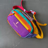 Bfarbige gestreifte Crossbodytasche mit lila, gelber und grüner Stoff sowie pinkem Riemen.