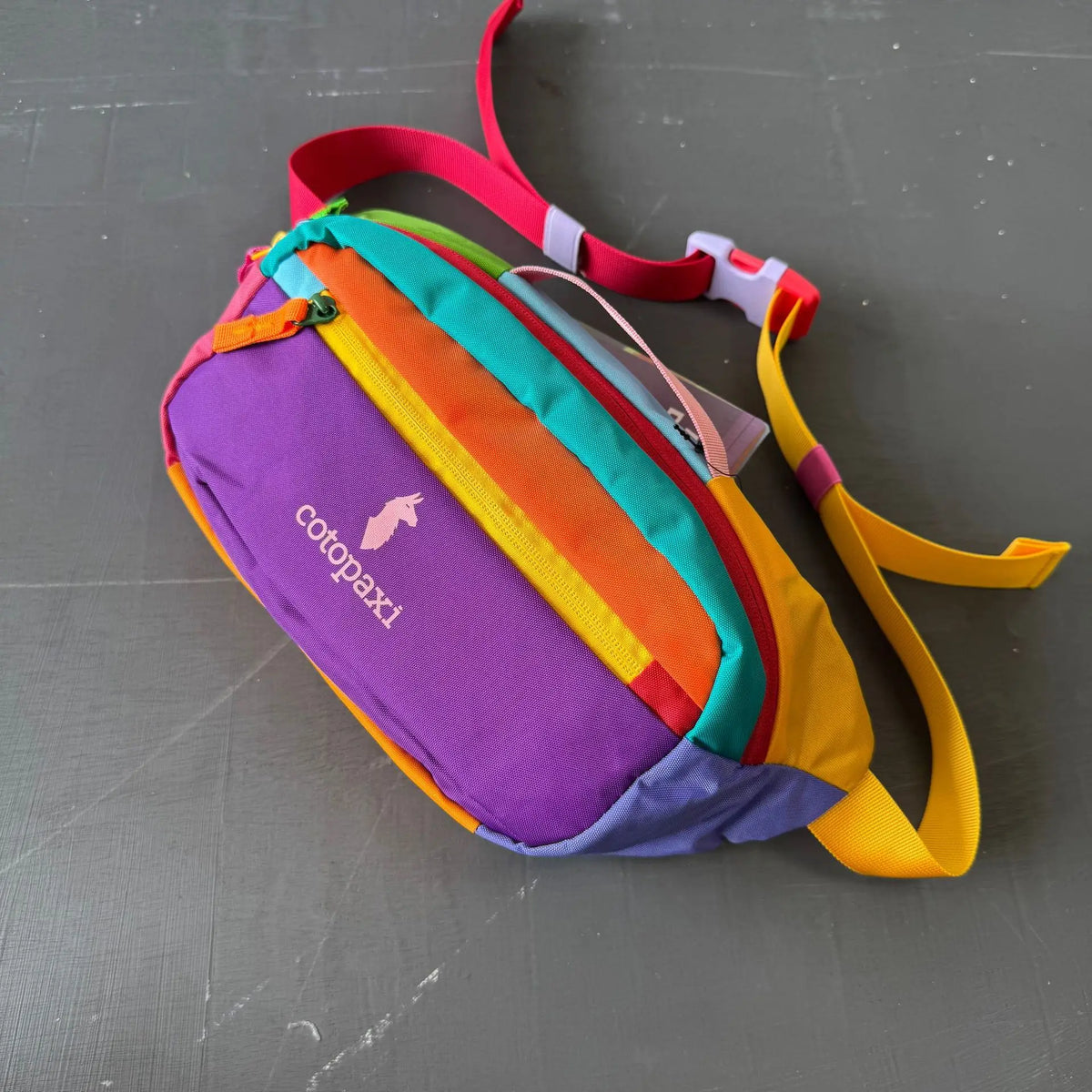 Bfarbige gestreifte Crossbodytasche mit lila, gelber und grüner Stoff sowie pinkem Riemen.