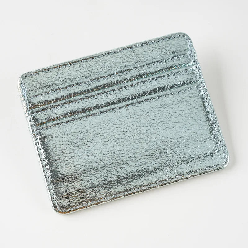 A silver-toned, textured leather mini wallet card holder with horizontal lines.