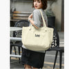 A woman models a cream-colored Korean style Oxford cloth tote bag in an outdoor setting.