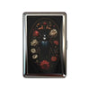 A vintage snap metal card holder with a dark background featuring an ornate floral design.