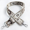 A beige and black floral patterned fabric strap with a silver buckle shown against a white background.