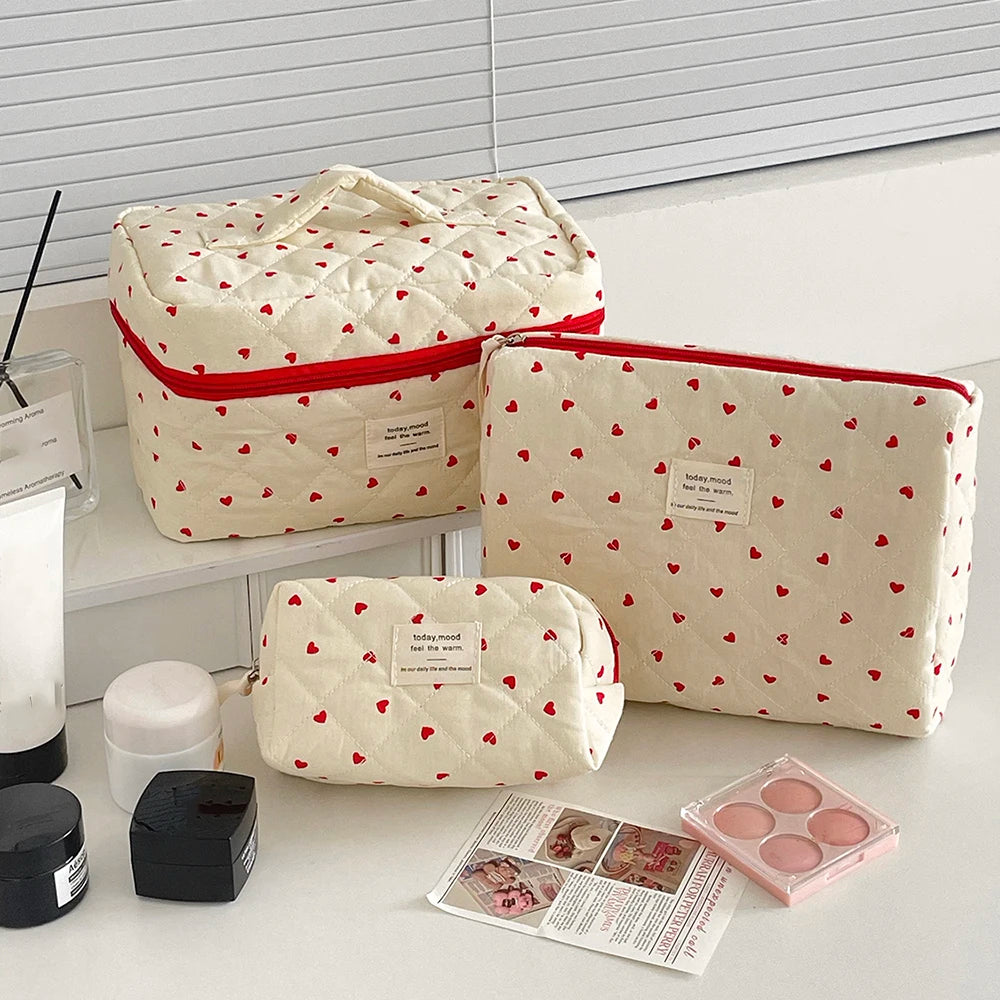 A cream quilted makeup bag with a red trim and a cartoon animal design, shown next to various beauty products.