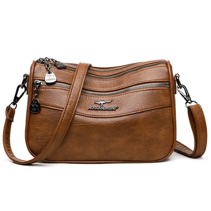 Bolso cruz de cuero marrón y moderno para mujer con herrajes plateados y cremallera.
