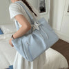 A light blue retro polka dot shoulder tote bag with a silver star charm is carried by a person in a white dress.