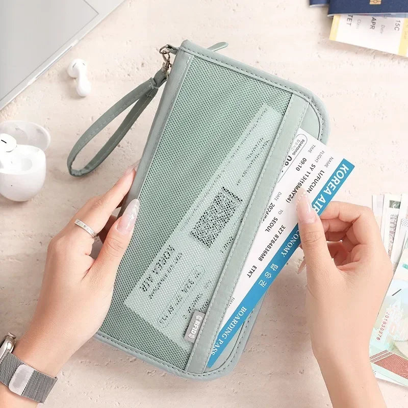 Une main tient un porte-documents organisateur de voyage vert clair pour cartes et documents sur un fond clair.