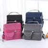 A collection of reusable insulated lunch bags in pink, navy blue, and gray are displayed on a white surface.