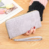 Cartera de tarjeta de cuero PU floral gris claro con cremallera y correa dorada sobre una superficie de madera.