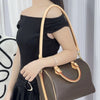 A model is shown carrying a brown leather shoulder bag with a tan strap against a white background.
