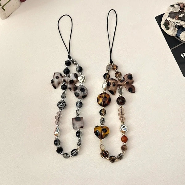 A pair of leopard print bowknot phone lanyards featuring heart and silver beads.