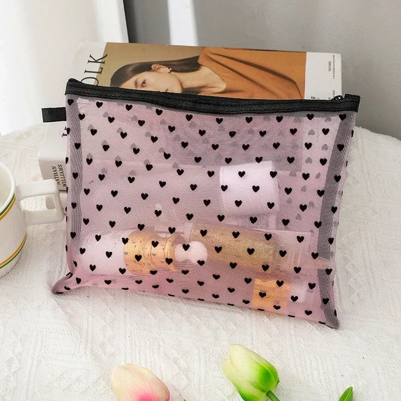 A mesh cosmetic storage pouch in lilac with gold accents is shown resting on a white surface.
