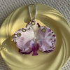 A realistic pink and purple Phalaenopsis orchid flower is displayed on a yellow plate, attached to a silver keychain.