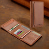 A brown leather multi-card wallet with a phone grip stand is shown on a dark surface.