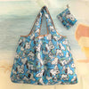 A light blue and white reusable shopping bag with a dog design, shown against a pale background.