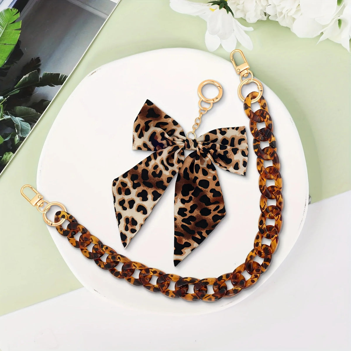 Leopardenmuster-Acryl-Taschenketten mit Schleifchen-Anhänger auf weißem Untergrund.