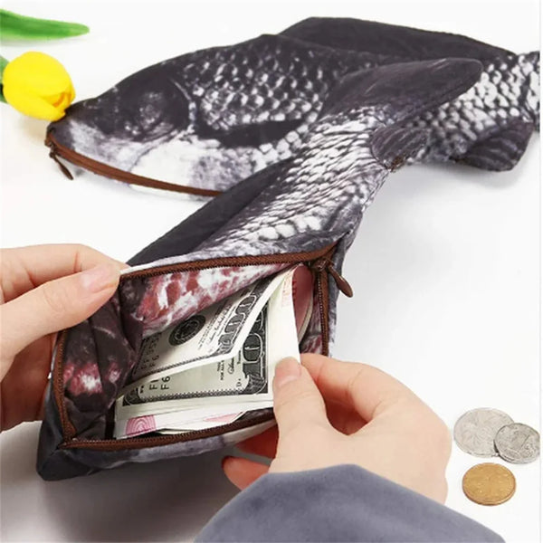 A hand is opening a dark patterned fish-shaped pencil case to reveal money inside.