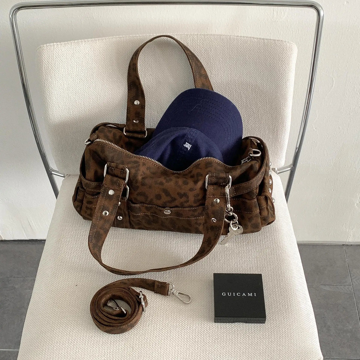 A brown leopard print Rivet Boston shoulder bag with a dark blue hat and a black box.