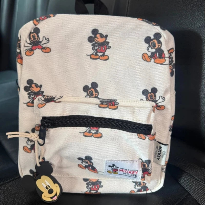 A beige backpack featuring Mickey Mouse print graphics on a light fabric.