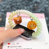 A hand is holding a replacement elastic watch strap for Huawei bands, which is light green and white, next to a smartphone.
