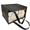 A black reusable tote bag filled with stacked white paper bags for grocery shopping.