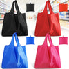 A collection of reusable foldable grocery tote bags in black, red, blue, and pink.