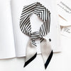 Foulard de soie rayé noir et blanc noué en nœud, présenté sur une page blanche.